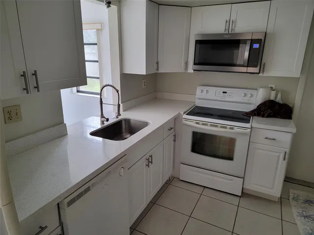 a kitchen with white cabinets a sink and white appliances