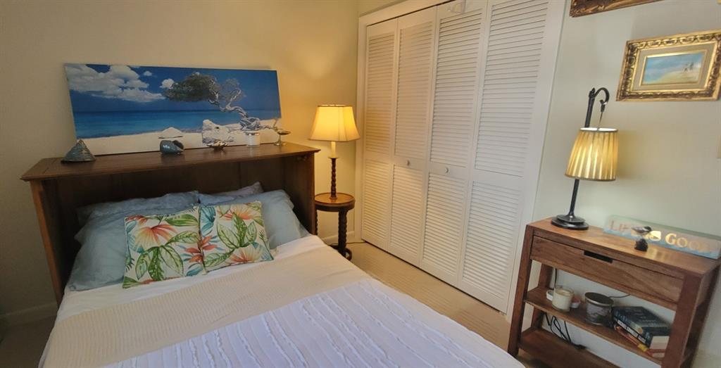 1800 Northeast 39th Court, Unit 1001 Pompano Beach, FL 33064 - Photo 31 of 39 a bed sitting in a bedroom next to a lamp on a small table and a flat screen tv