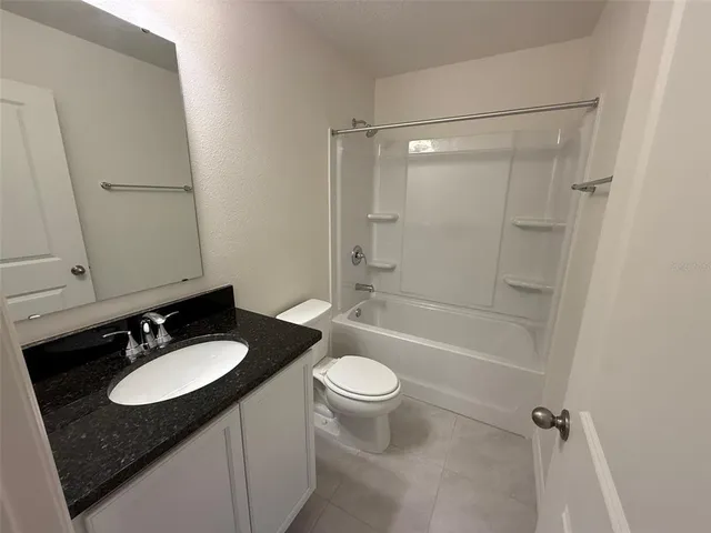 a bathroom with a granite countertop sink toilet mirror and shower