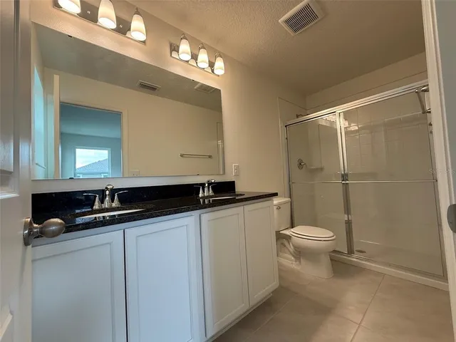 a bathroom with a granite countertop sink mirror vanity and toilet
