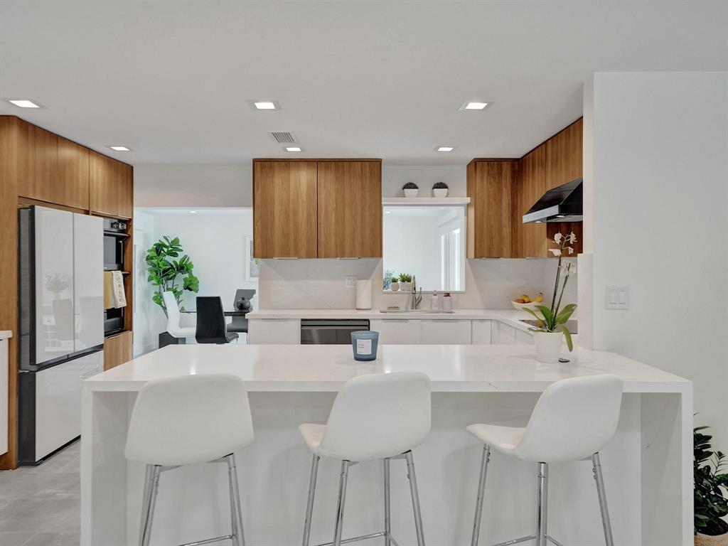 a kitchen with stainless steel appliances kitchen island granite countertop a sink and refrigerator