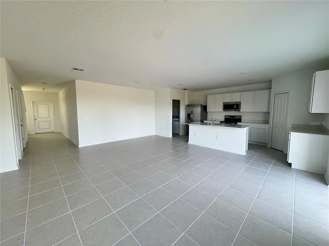 a large white kitchen with stainless steel appliances a sink a stove a microwave and cabinets