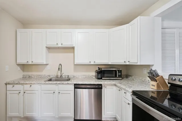 a kitchen with granite countertop a sink stove and cabinets