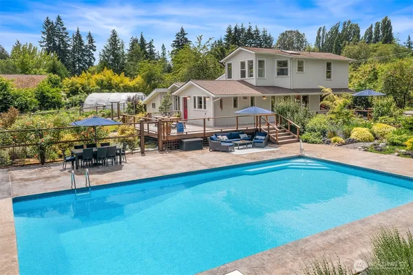 an aerial view of a house with swimming pool and large trees