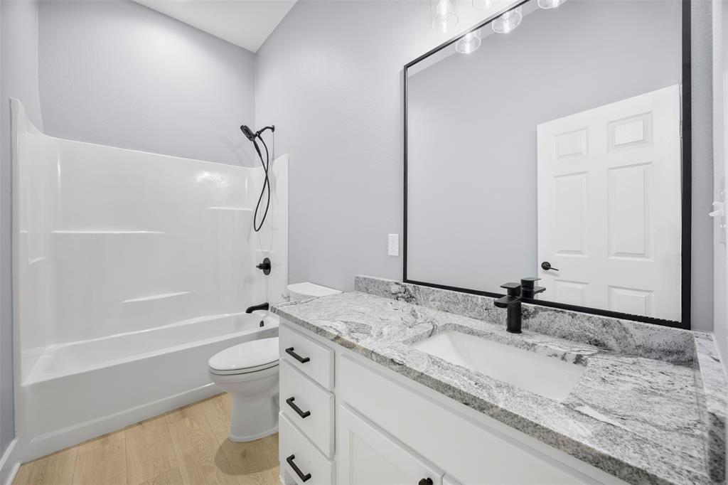 121 Brazier Road Ennis, TX 75119 - Photo 19 of 31 a bathroom with a granite countertop sink a toilet and a bathtub