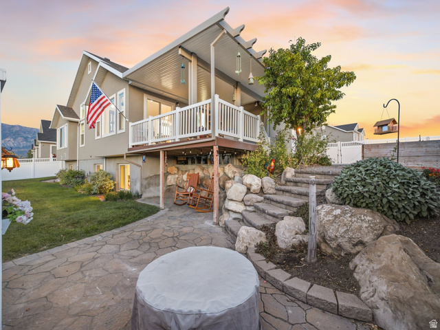 7 Sterling Loop Vineyard, UT 84059 - Photo 3 of 43 Multi-level outdoor living space featuring an upper deck with white railings, a covered lower patio, and a stone paver patio