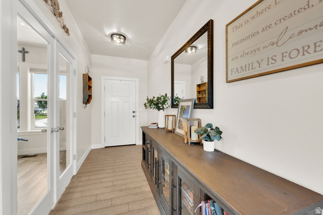 1857 Thunder Gulch Road Eagle Mountain, UT 84005 - Photo 4 of 50 Entryway featuring wood-finish flooring, a white paneled entry door, and a built-in console cabinet with glass-front doors
