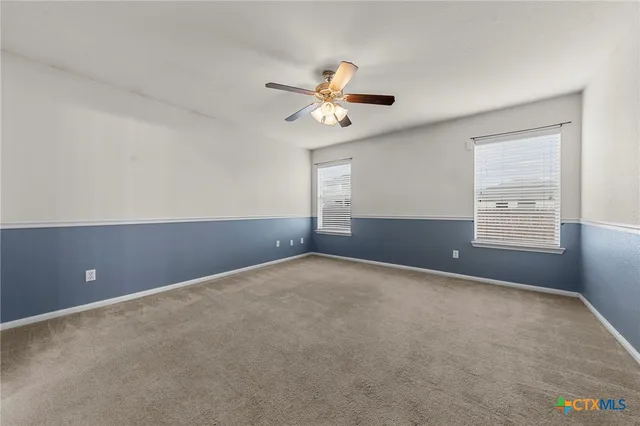 an empty room with windows and fan