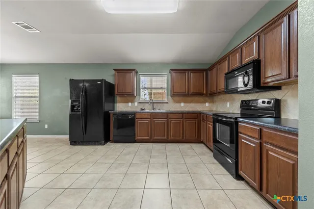 a kitchen with stainless steel appliances granite countertop a refrigerator and a stove top oven
