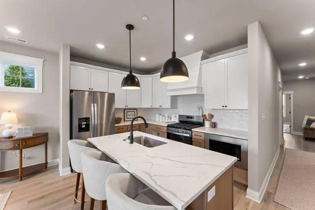 a kitchen with kitchen island a stove a sink a refrigerator and chairs