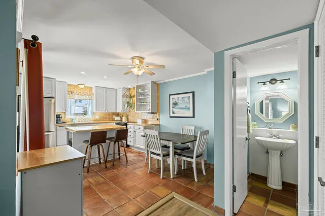 a kitchen with stainless steel appliances granite countertop a stove top oven a refrigerator a dining table and chairs with wooden floor