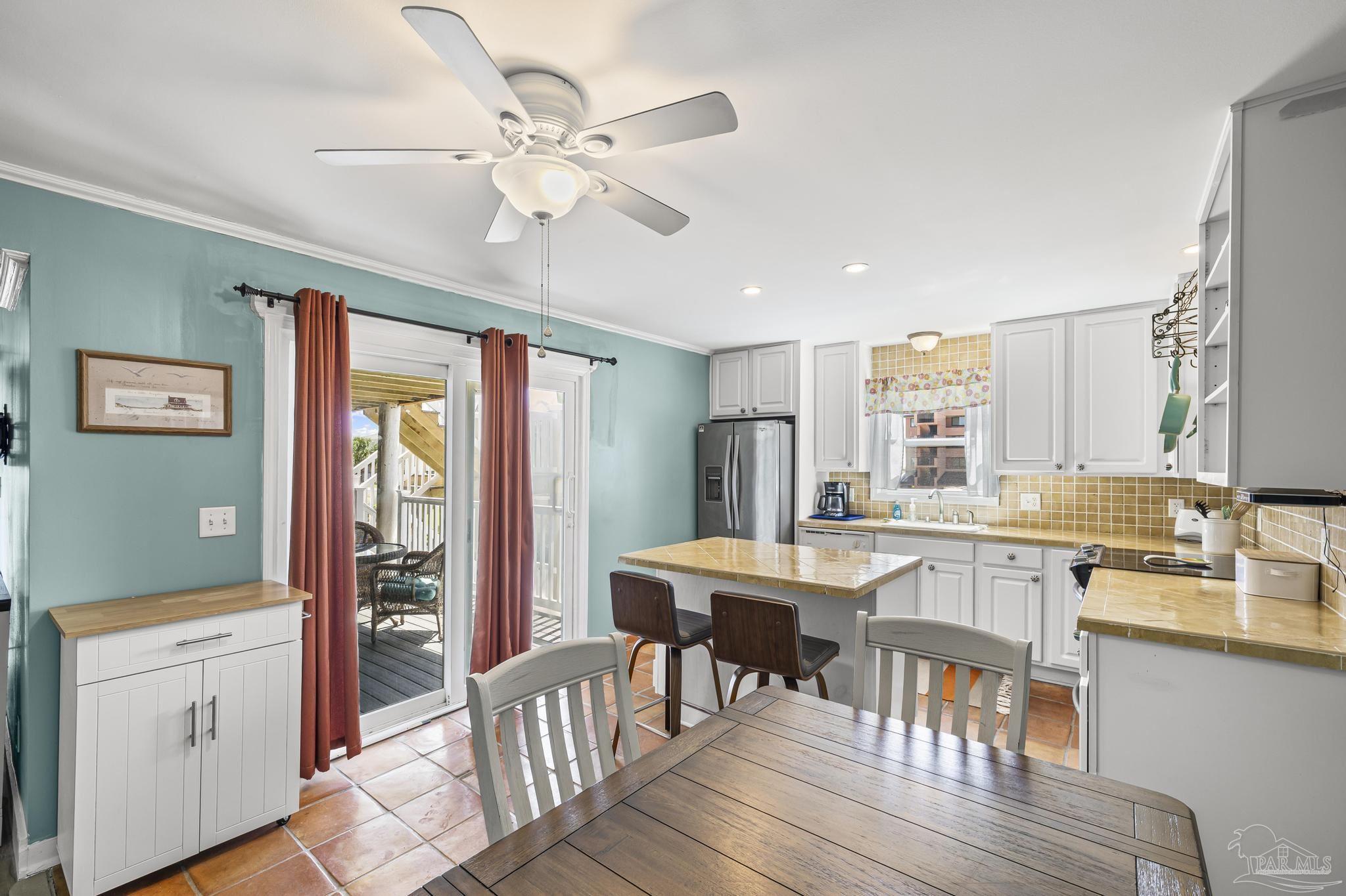 1100 Fort Pickens Road, Unit A13 Pensacola Beach, FL 32561 - Photo 19 of 63 a kitchen with stainless steel appliances granite countertop a stove top oven a refrigerator a dining table and chairs with wooden floor