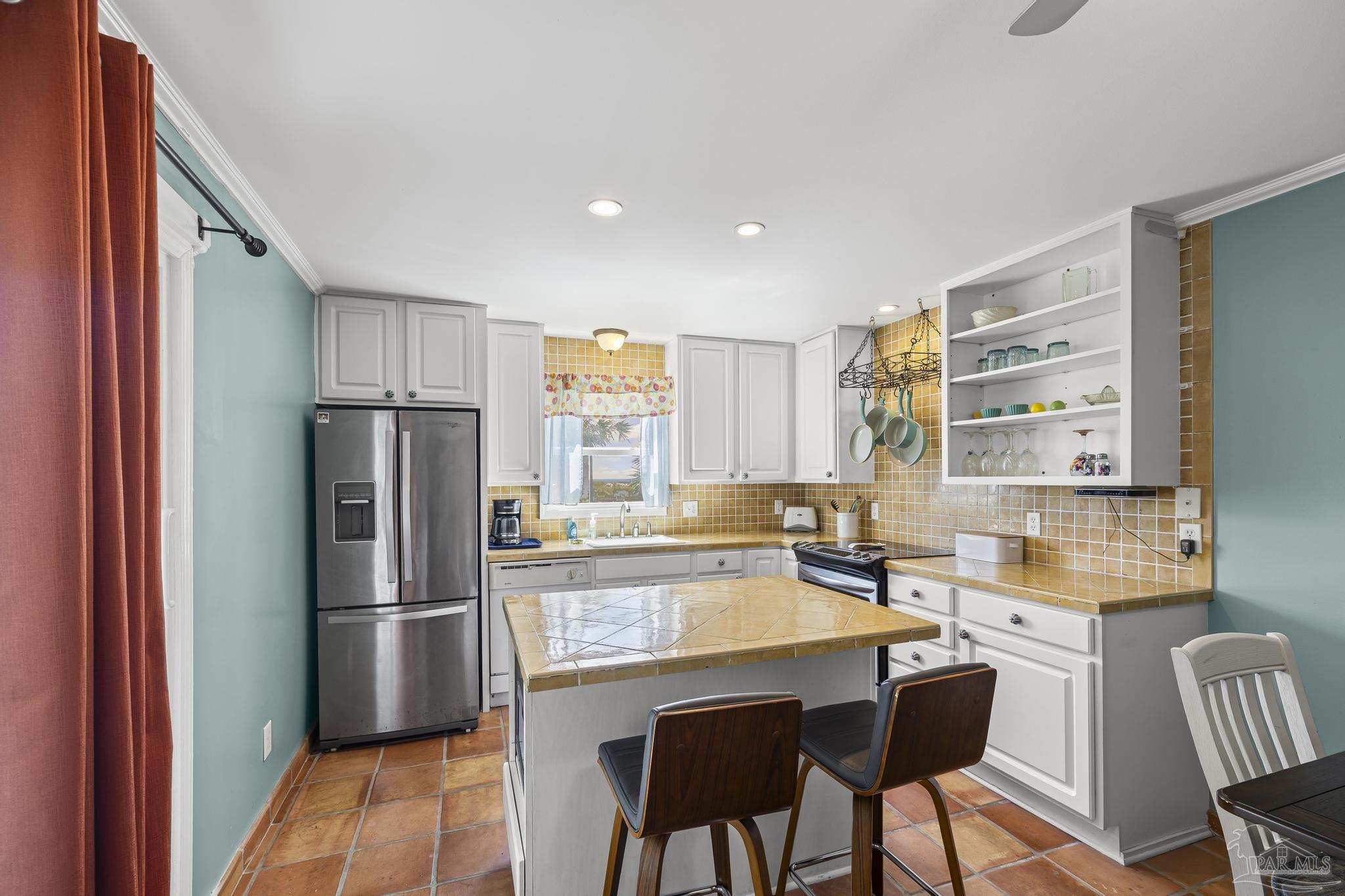 1100 Fort Pickens Road, Unit A13 Pensacola Beach, FL 32561 - Photo 21 of 63 a kitchen with refrigerator cabinets dining table and chairs
