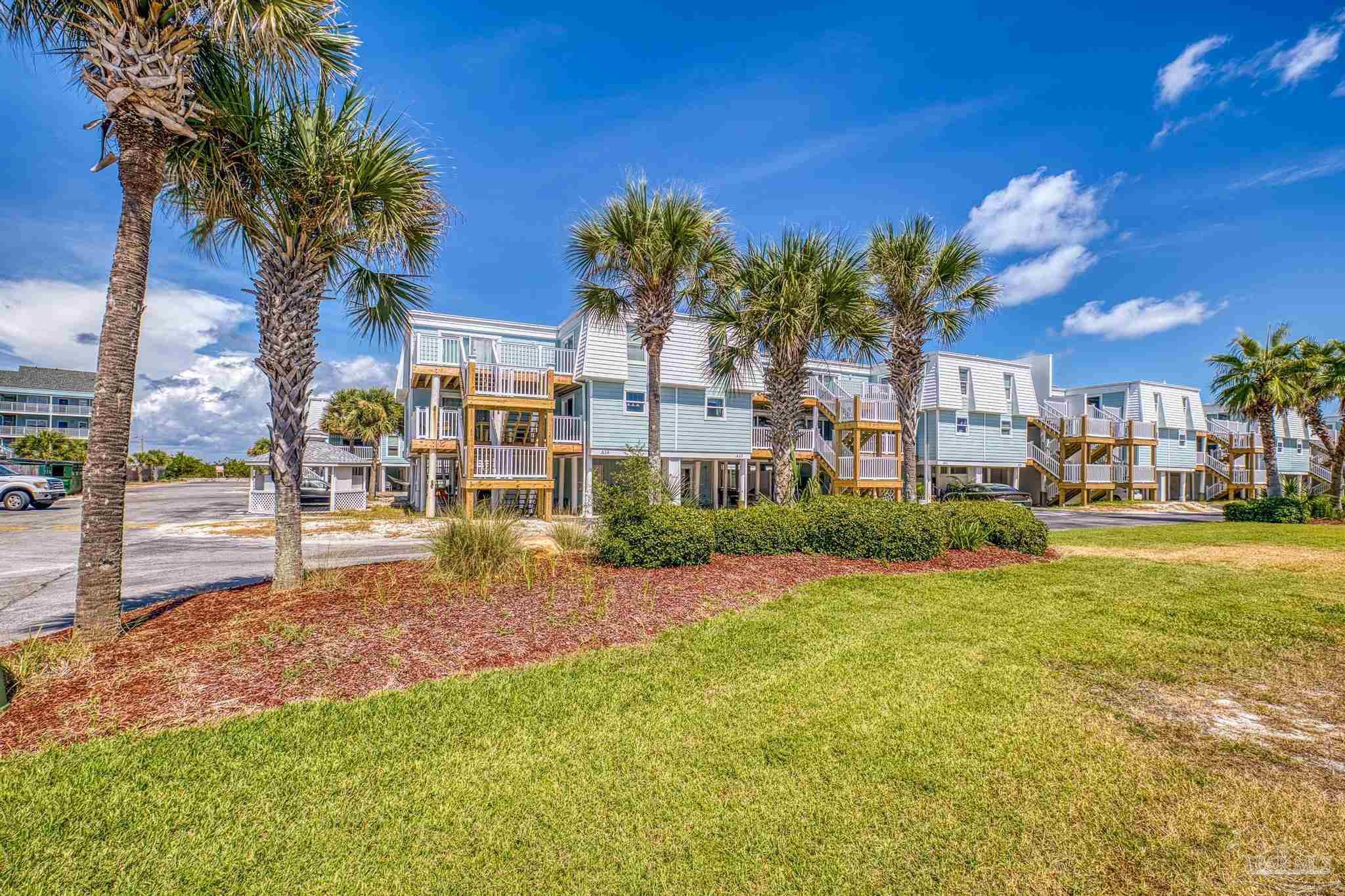1100 Fort Pickens Road, Unit A13 Pensacola Beach, FL 32561 - Photo 4 of 63 a view of a house with a big yard and large trees