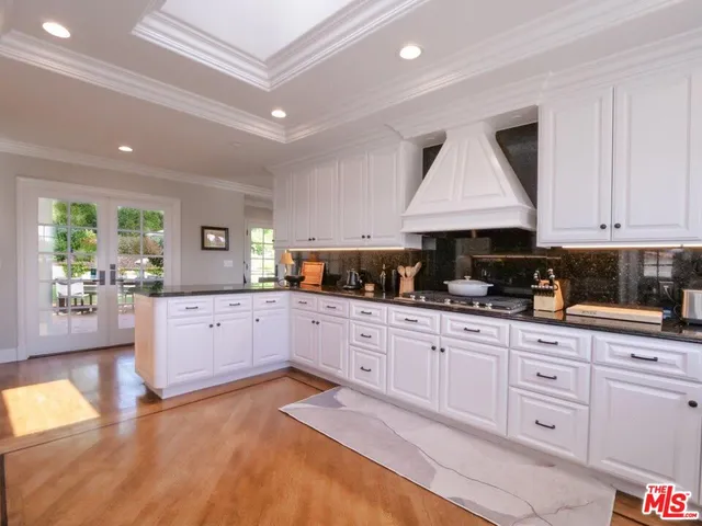 a large kitchen with granite countertop a stove a sink a window and white cabinets