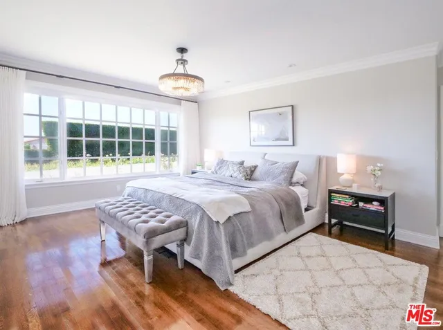 a bedroom with a bed and a table in it with wooden floor