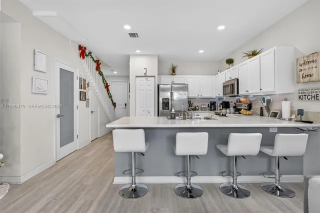 a kitchen with stainless steel appliances granite countertop a white cabinets and chairs