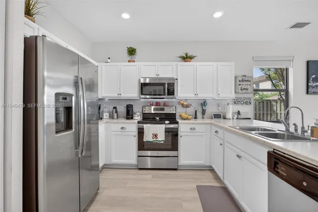 a kitchen with white cabinets and stainless steel appliances