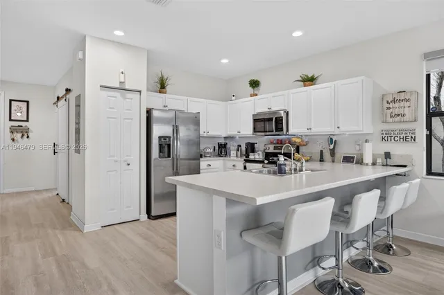 a kitchen with stainless steel appliances granite countertop a refrigerator a stove top oven a sink and cabinets