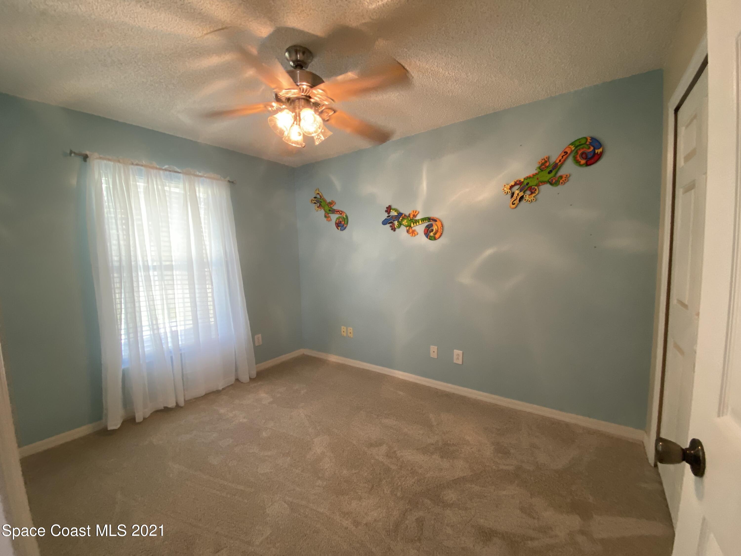 2481 Anchor Road Southeast Palm Bay, FL 32909 - Photo 29 of 32 an empty room with windows and chandelier fan