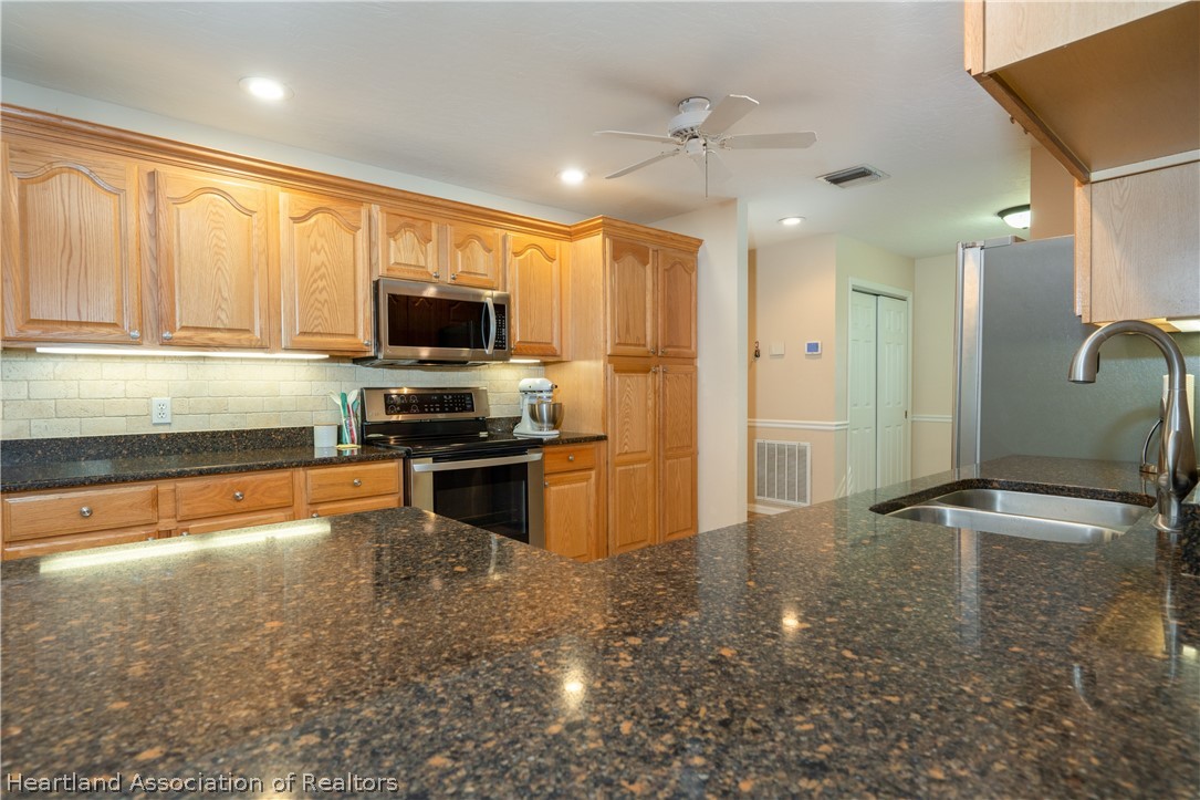 4021 Loquat Road Sebring, FL 33875 - Photo 6 of 26 a kitchen with granite countertop a refrigerator and a stove top oven