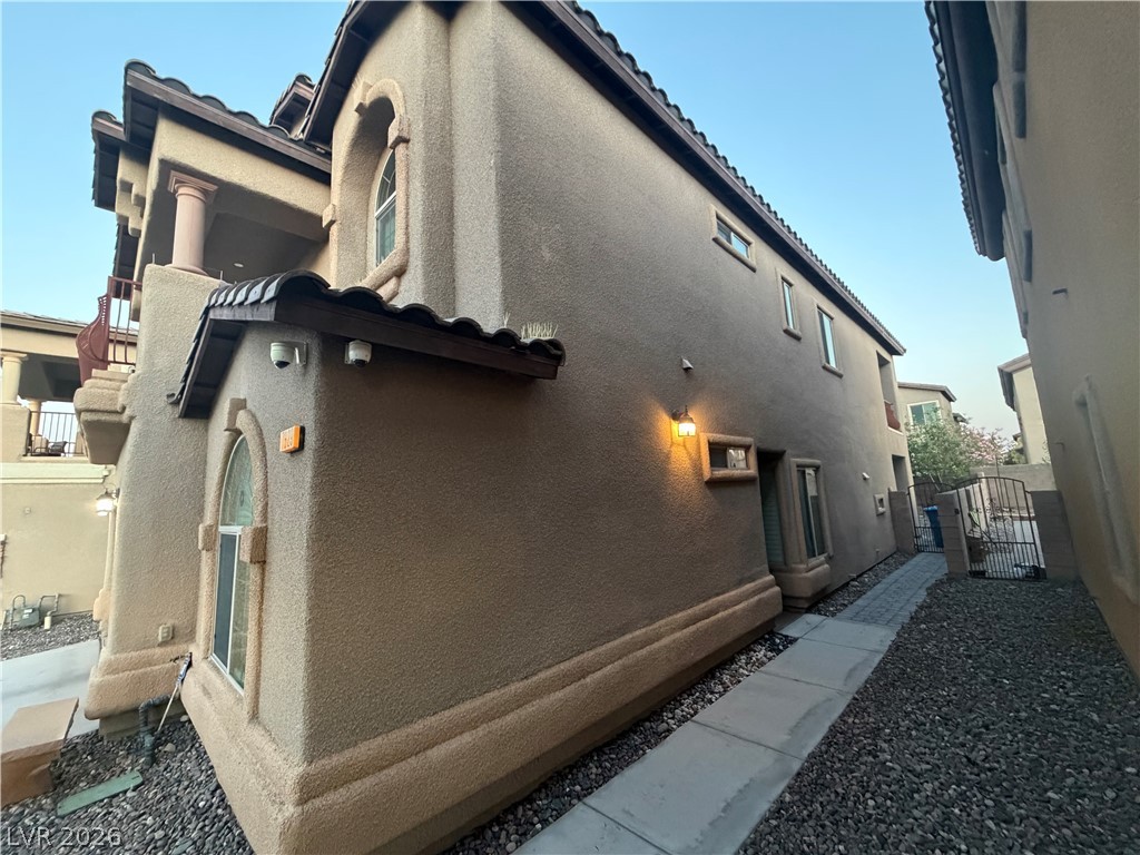 7629 Rory Court Las Vegas, NV 89129 - Photo 3 of 25 A well-maintained side yard offers a paved walkway alongside a multi-level dwelling.