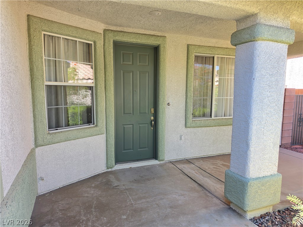 209 Opera House Street Henderson, NV 89012 - Photo 36 of 45 A covered concrete entryway features stucco accents and a solid green front door.