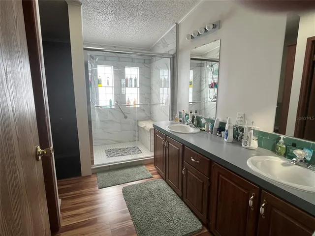 a bathroom with a double vanity sink a mirror and a shower