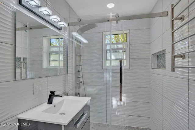 a bathroom with a sink a glass door shower and a mirror