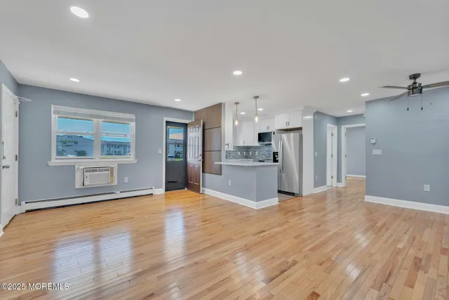 a view of a kitchen with kitchen island a sink wooden floor and a refrigerator