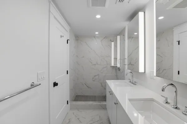a bathroom with a double vanity sink a toilet and shower