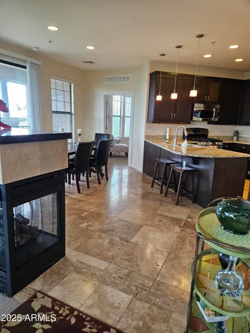 a living room with stainless steel appliances kitchen island granite countertop furniture a rug and a fireplace