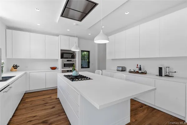 a kitchen with stainless steel appliances a stove a sink a refrigerator white cabinets and wooden floor