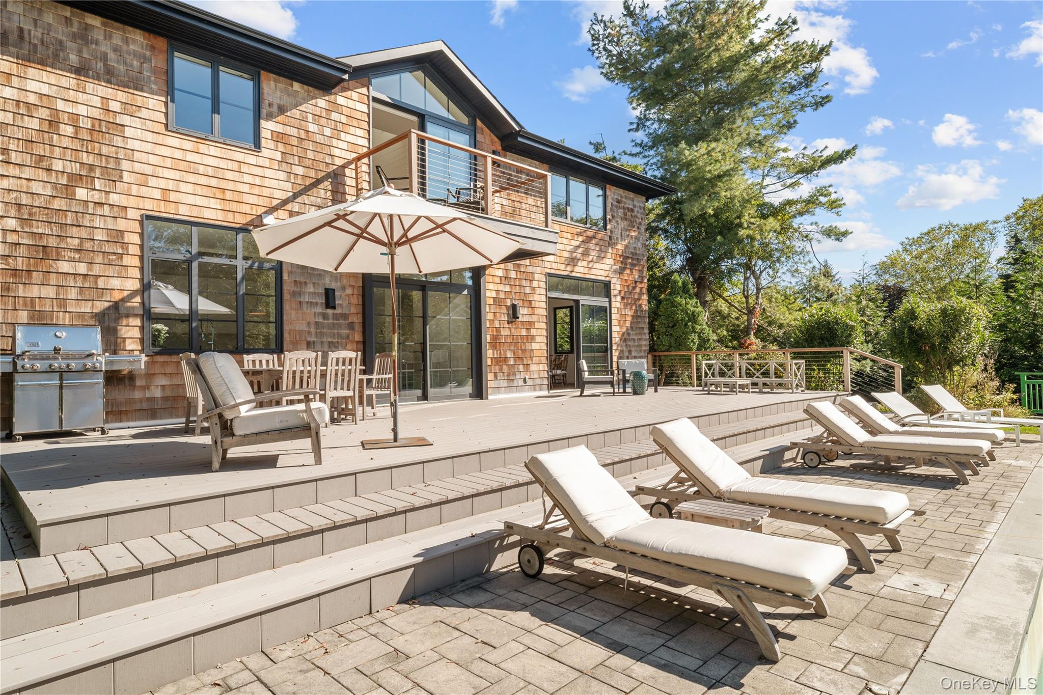 15 Atterbury Road Southampton, NY 11968 - Photo 38 of 46 a view of a patio with couches and table and chairs under an umbrella