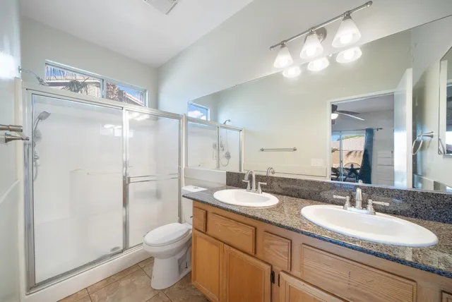 a bathroom with a granite countertop sink toilet a large mirror a shower and vanity