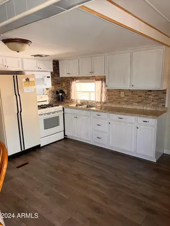 a kitchen with granite countertop a sink a stove a refrigerator and white cabinets