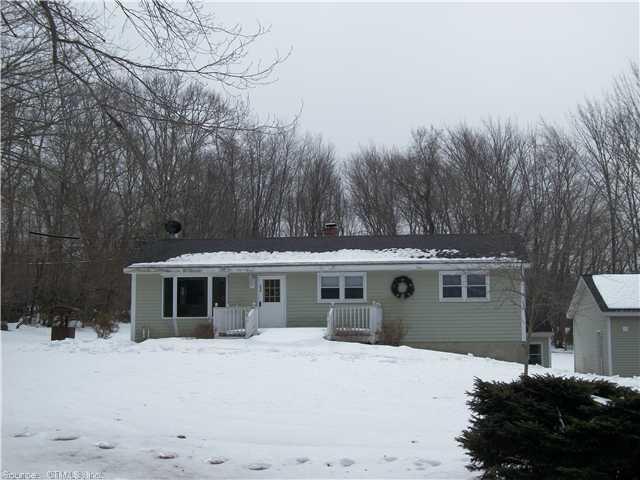 a front view of a house with a yard covered with snow and trees
