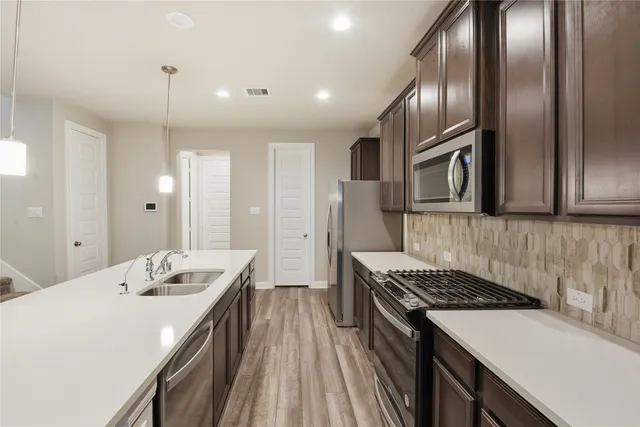 a kitchen that has a sink stainless steel appliances and cabinets