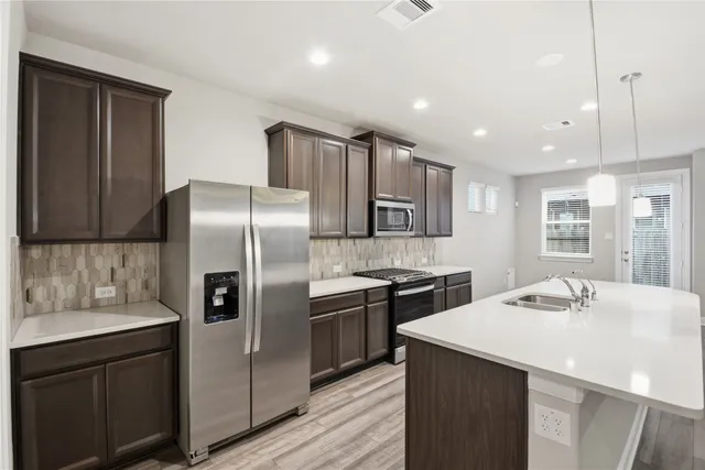 a kitchen with stainless steel appliances kitchen island a sink stove and refrigerator