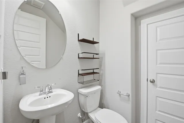 a bathroom with a toilet a sink and mirror