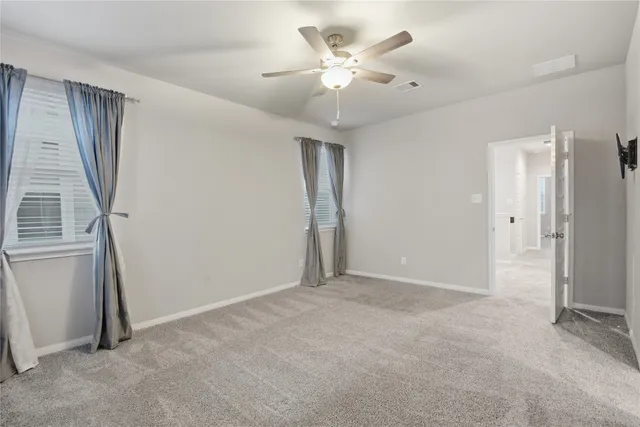 an empty room with windows and fan