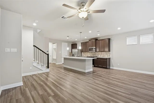 a large white kitchen with kitchen island a stove a sink dishwasher and a dining table with wooden floor