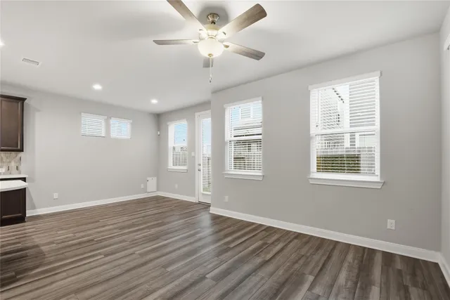 a view of an empty room with a window and wooden floor