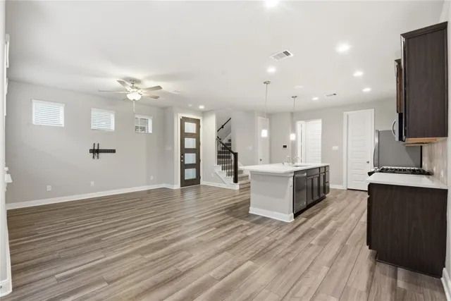 a large kitchen with stainless steel appliances a large counter top a sink a refrigerator and a stove