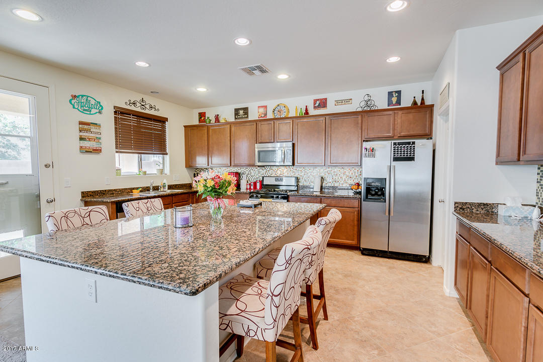 2099 South Martingale Road Gilbert, AZ 85295 - Photo 14 of 43 a kitchen with granite countertop a center island stainless steel appliances cabinets a sink and a window