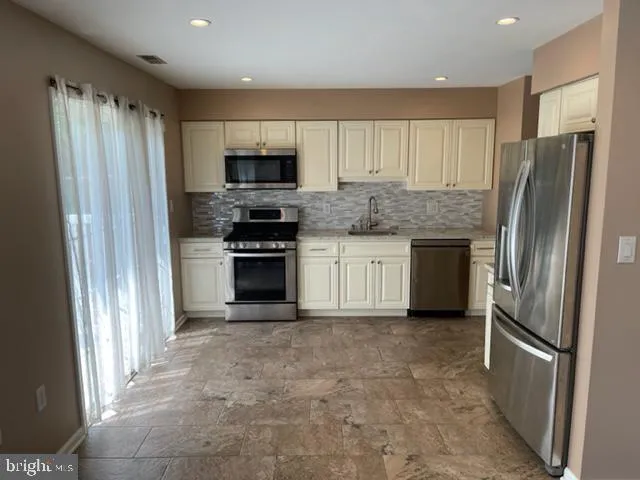 a kitchen with stainless steel appliances granite countertop a refrigerator a stove a sink and a microwave