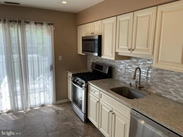 a kitchen with stainless steel appliances granite countertop a sink a stove and a microwave