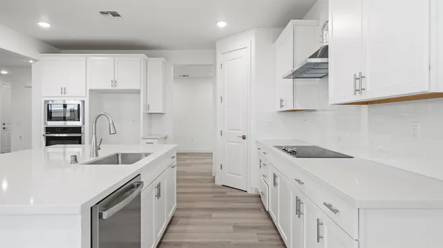a kitchen with white cabinets appliances and a sink