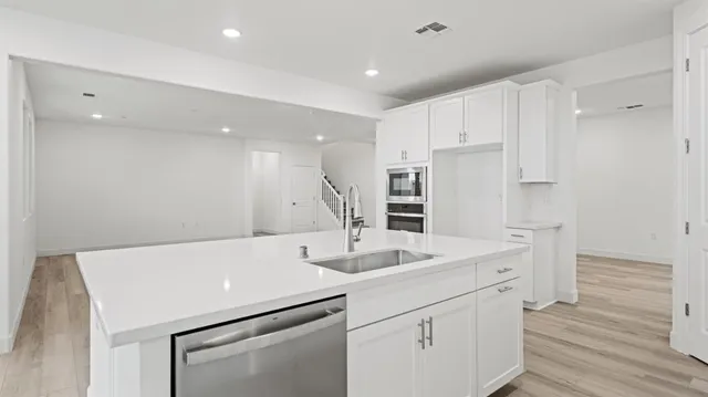 a view of a kitchen counter space with white cabinets and wooden floor