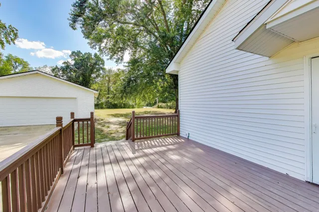 a view of a deck with wooden floor and fence next to a yard